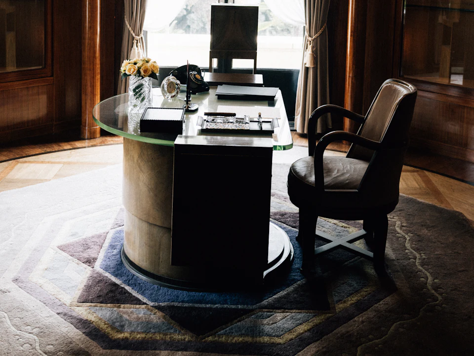 Wood-panelled executive office with a leather chair and glass desk