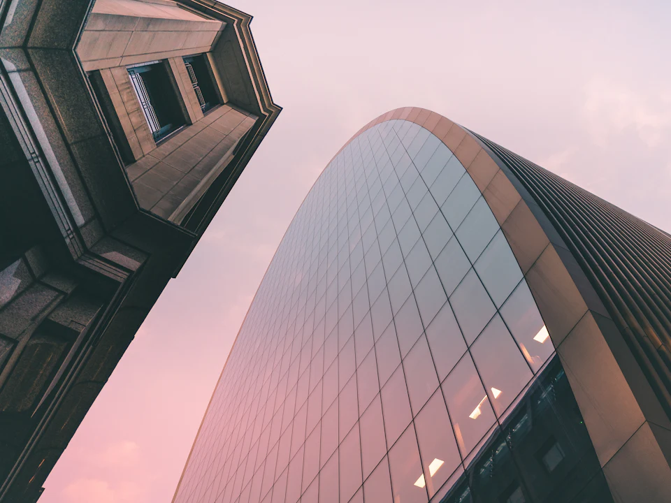 Glass skyscraper rising into a pink evening sky